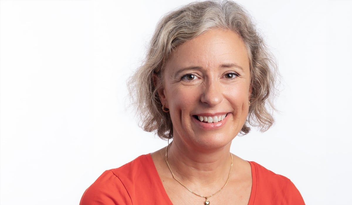 En kvinna i röd skjorta som ler mot kameran.