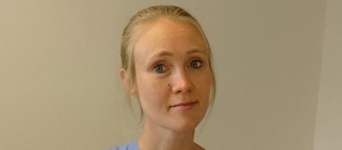 En kvinna i operationskläder håller i en flaska med medicin.