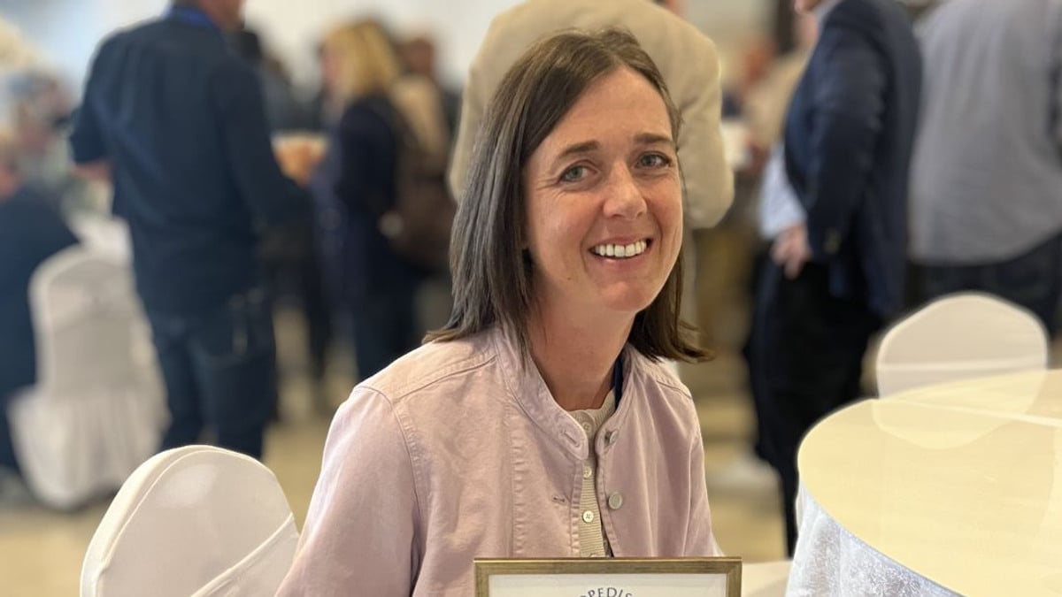 En kvinna sitter på en stol och håller i en plakett.