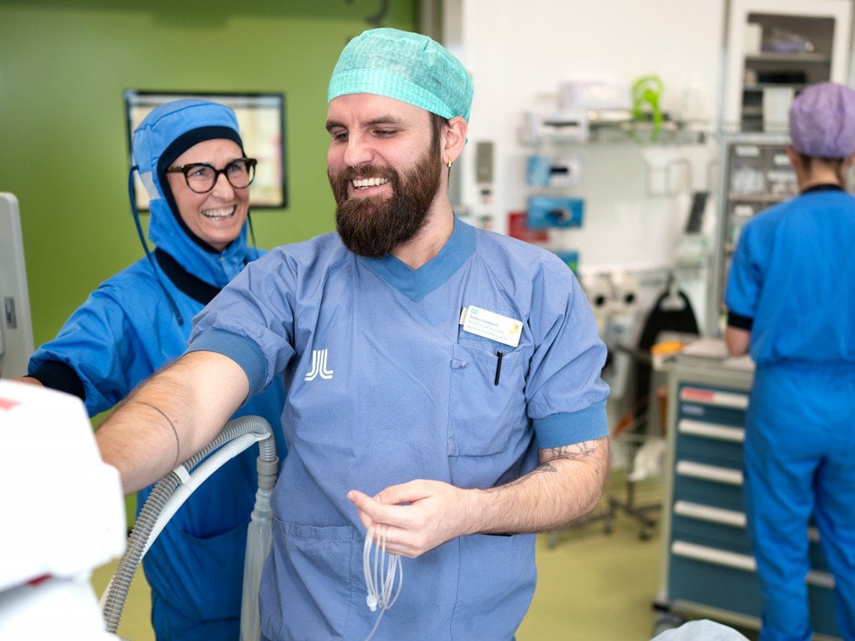 En man i operationskläder och en kvinna i operationskläder på ett sjukhus.