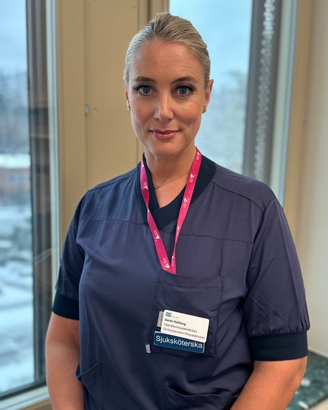 En kvinna i operationskläder står framför ett fönster.