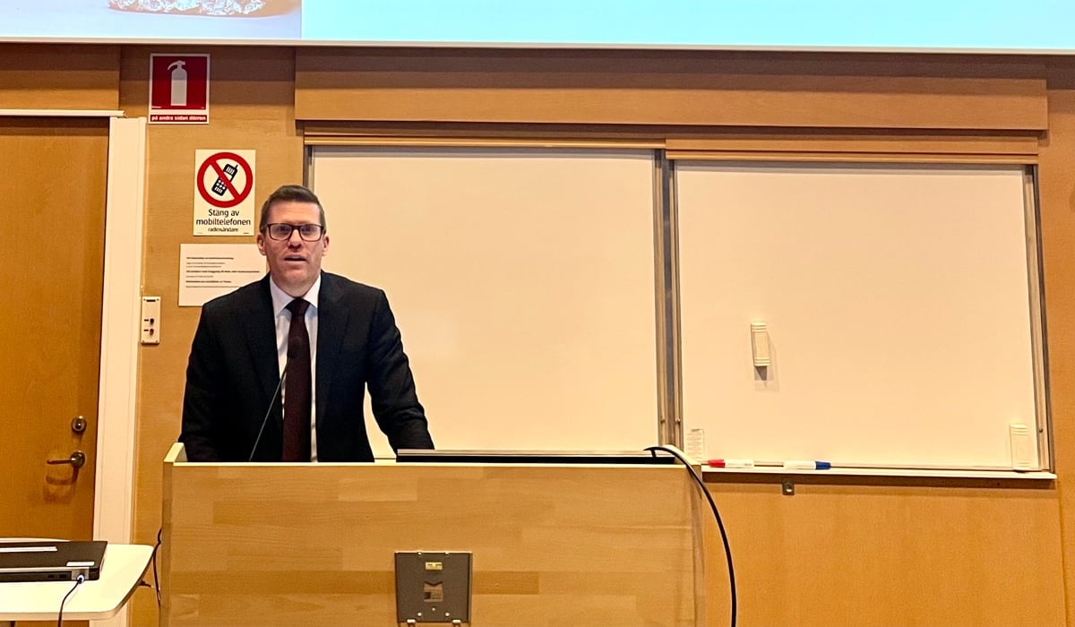 En man står på ett podium framför en projektionsskärm.