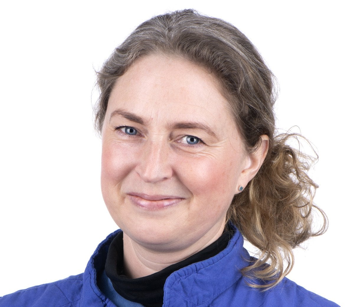 En kvinna i blå jacka ler.
