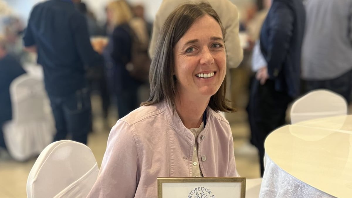 En kvinna sitter på en stol och håller i en plakett.