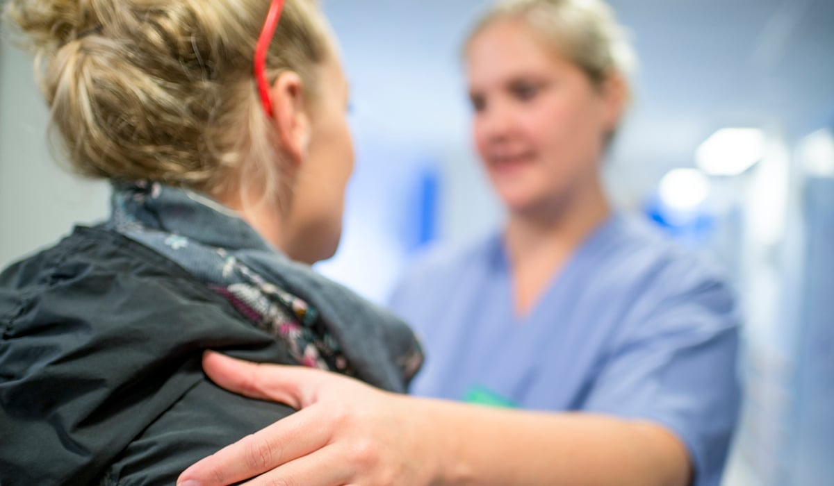 Sjukvårdspersonal som har handen på en patients axel