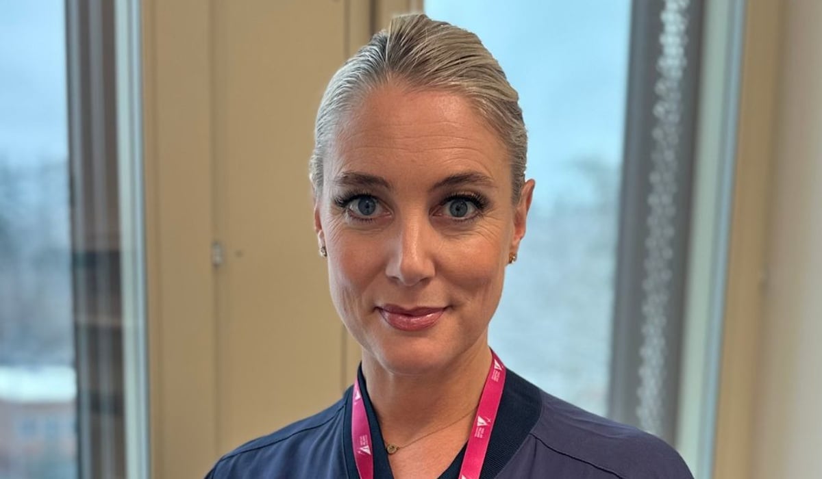 En kvinna i operationskläder står framför ett fönster.