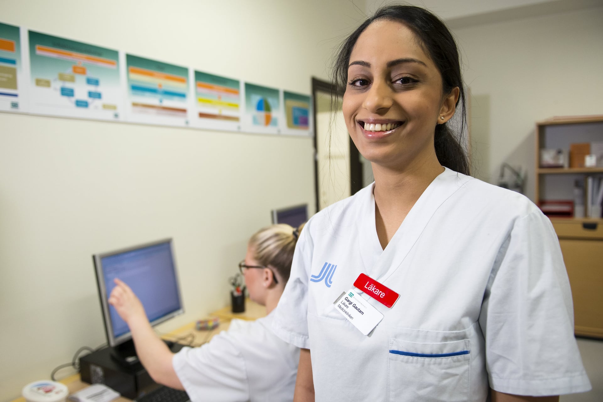 En kvinna i operationskläder står framför en dator.